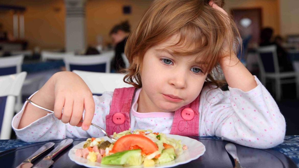 Kind sitzt lustlos vorm Teller voller Essen