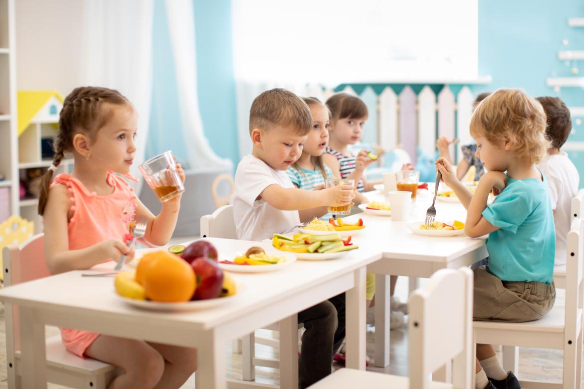 Kinder aus der Kita frühstücken gemeinsam an einem Tisch